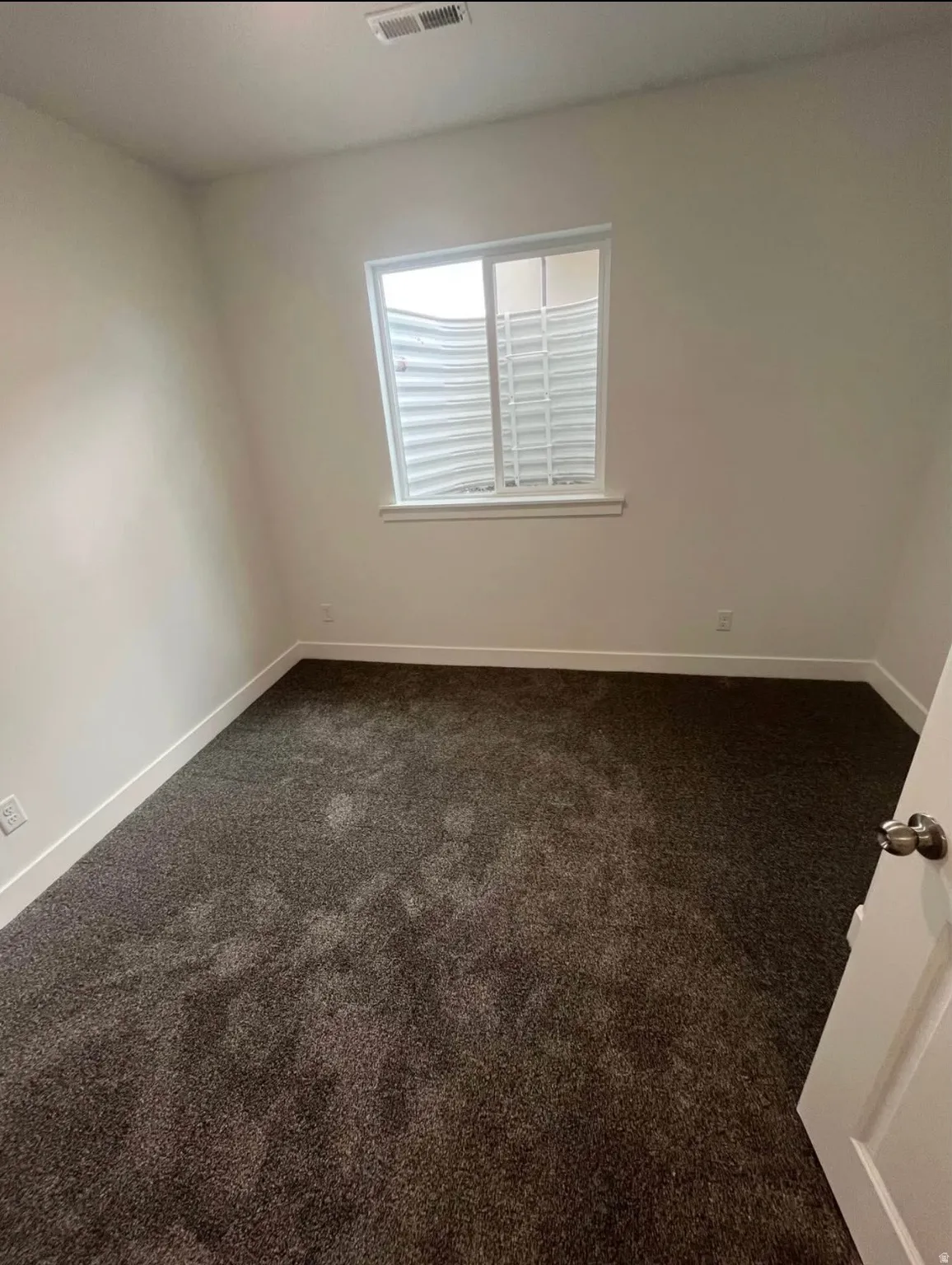 Empty room with dark carpet and baseboards