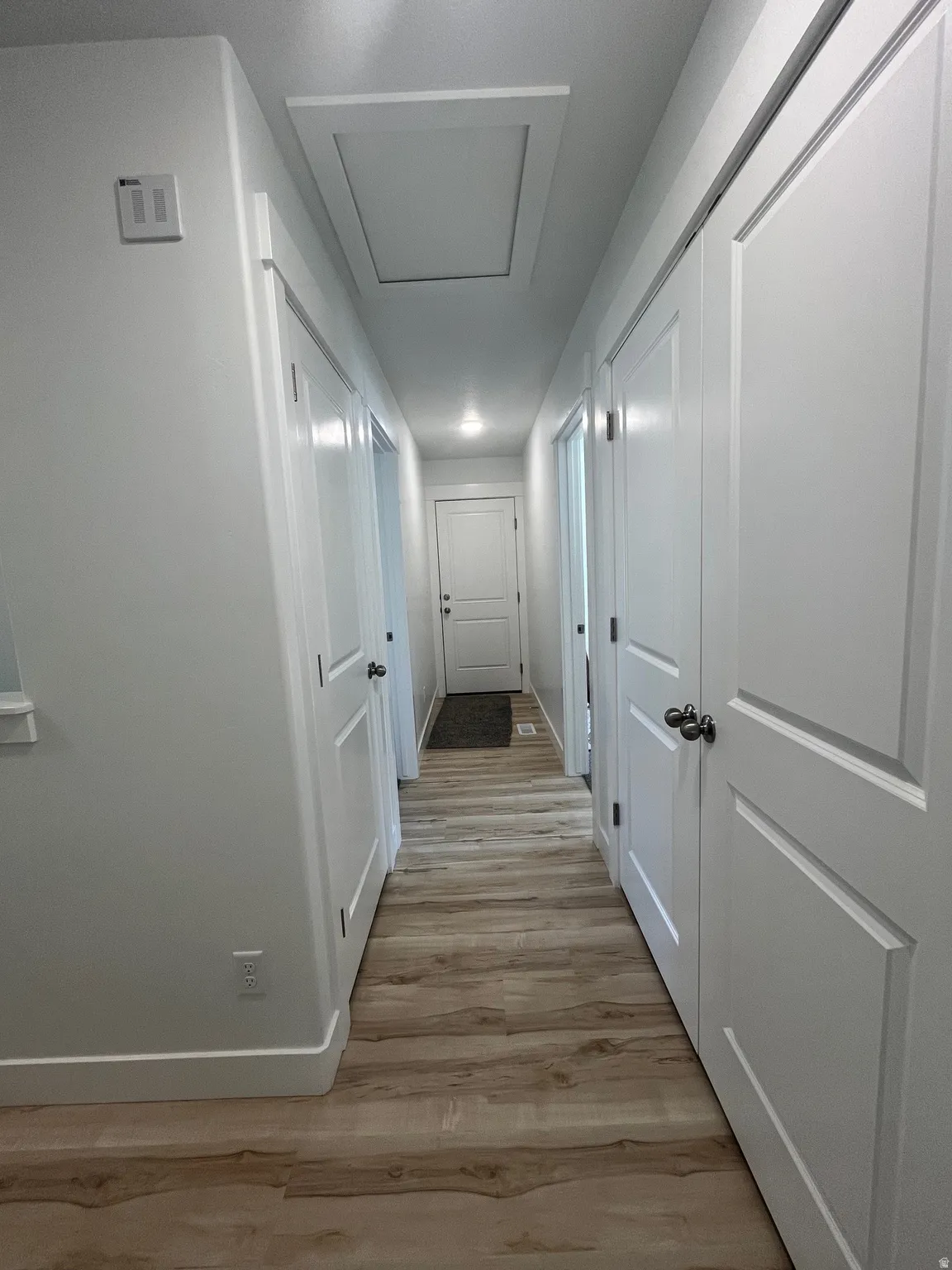 Hallway featuring light wood-style flooring and baseboards
