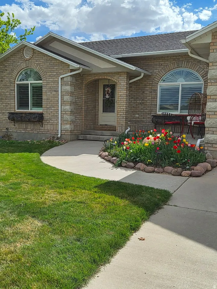 View of exterior entry with a yard, brick siding, and a shingled roof