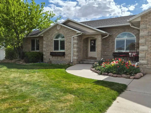 View of front of house with a front yard, brick siding, and a shingled roof
