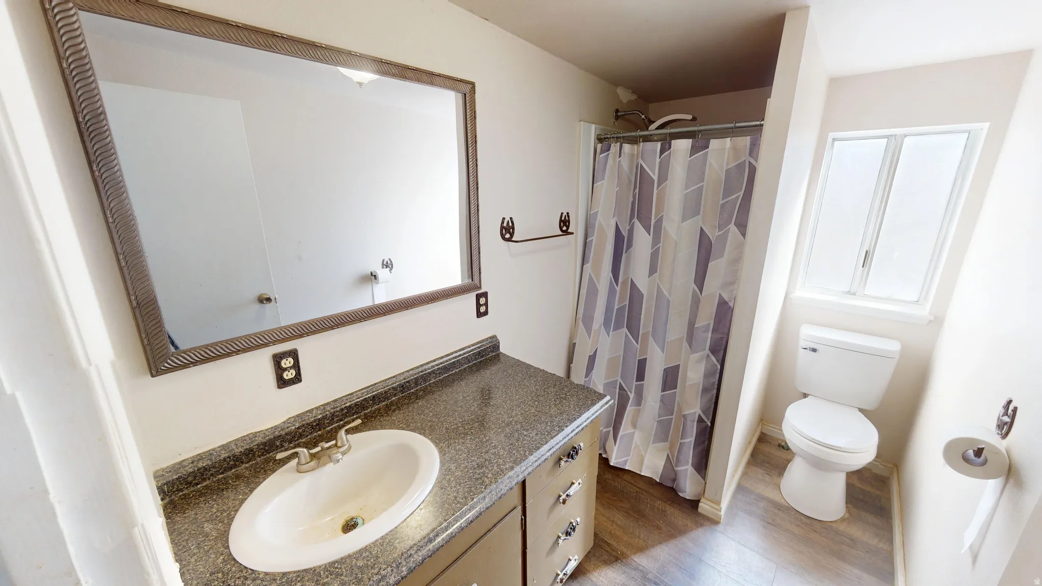 Bathroom featuring a shower with shower curtain, vanity, and dark wood-type flooring