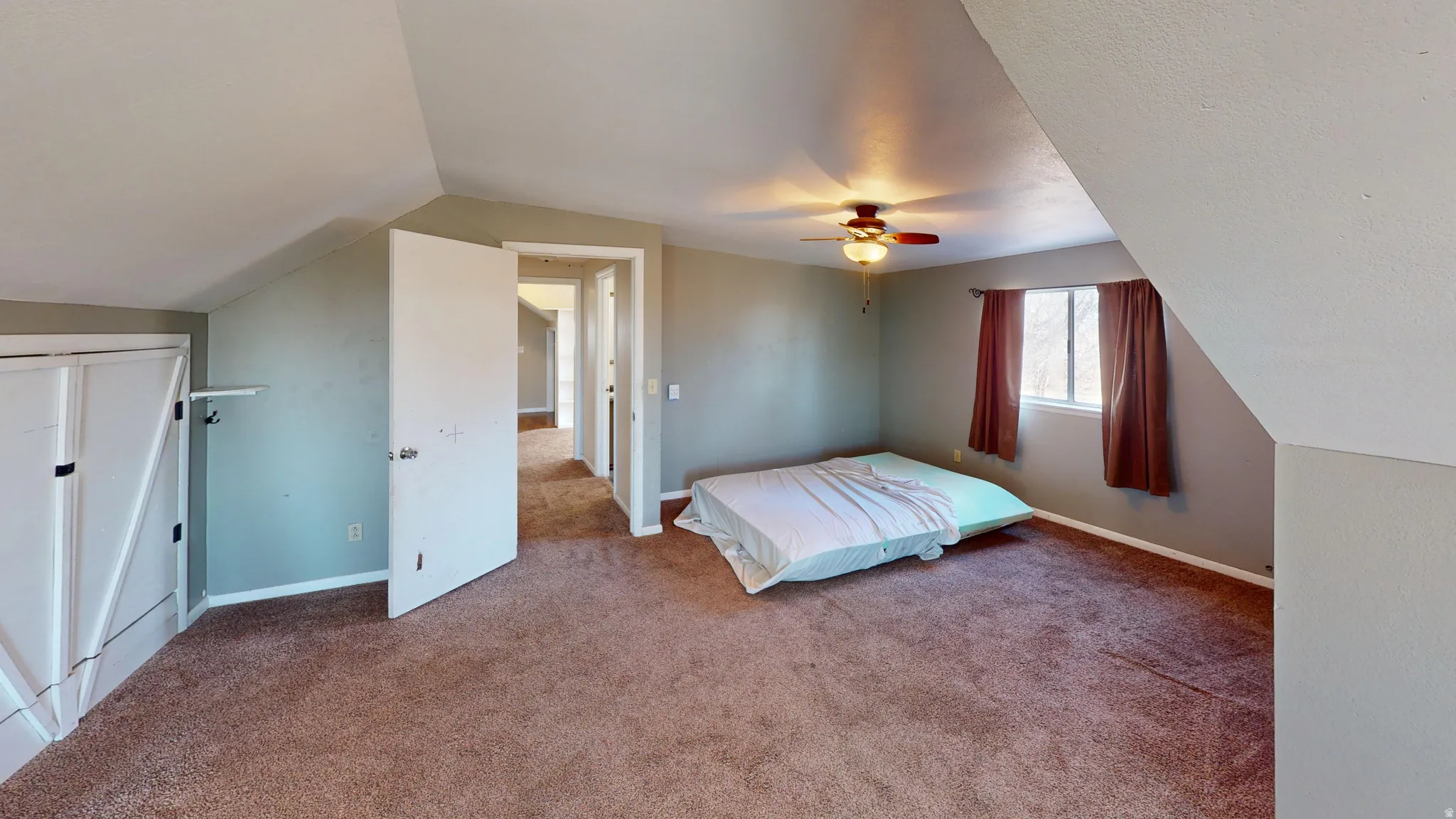 Carpeted bedroom featuring lofted ceiling and a ceiling fan