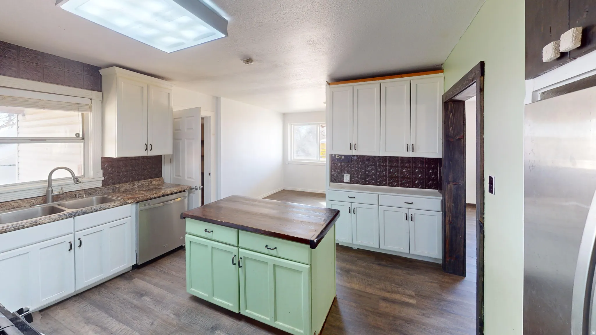 Dual tone kitchen with stainless steel appliances, wooden counters, backsplash, a center island, and dark wood-type flooring