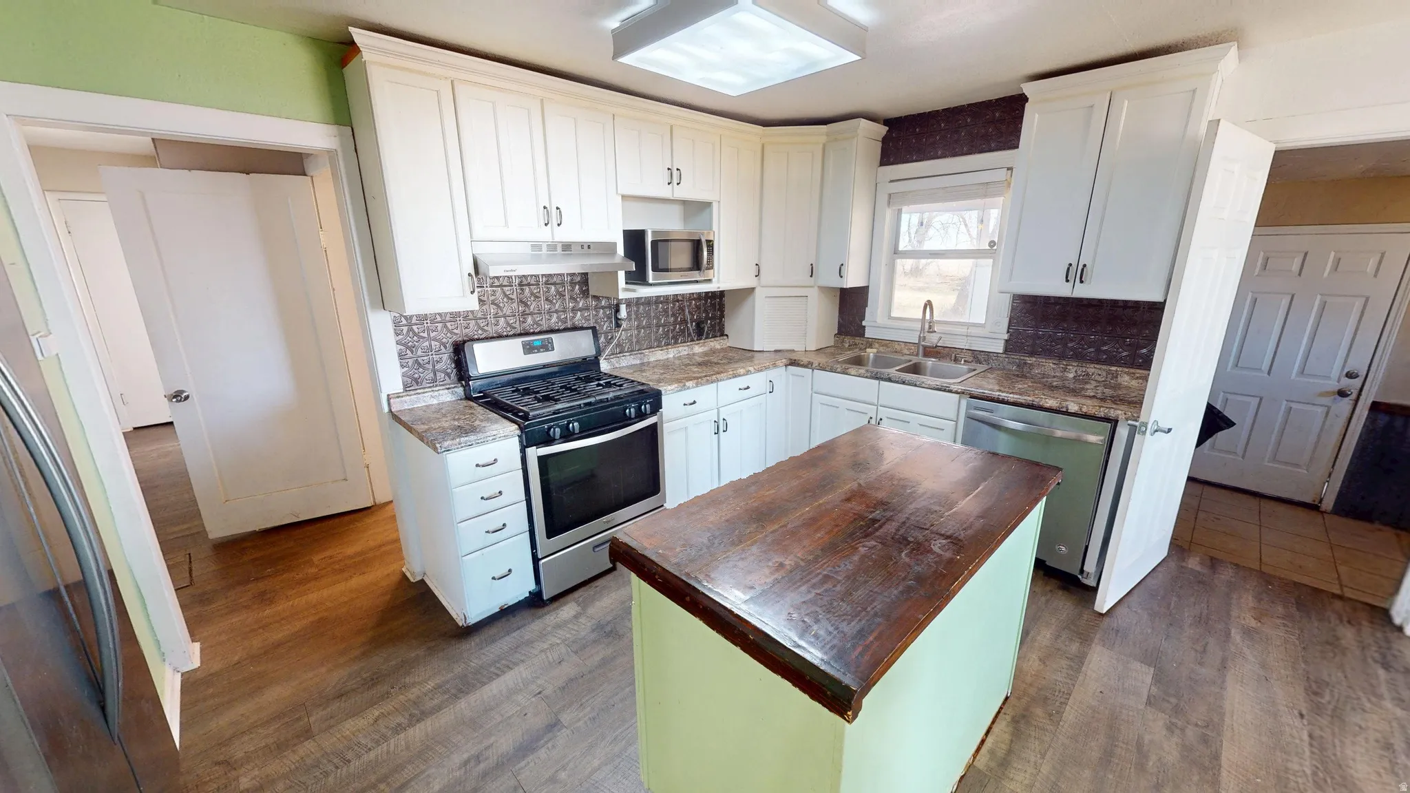 Kitchen with stainless steel appliances, a center island, wooden counters, dark wood finished floors, and backsplash