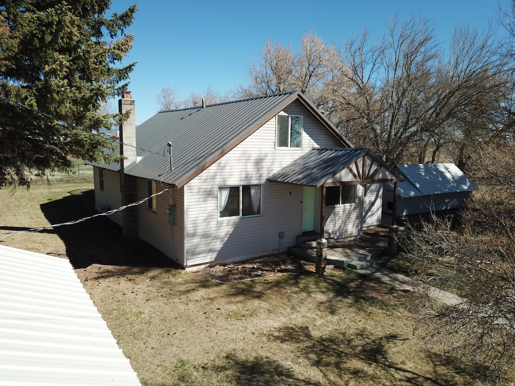 View of side of home with a metal roof and a chimney