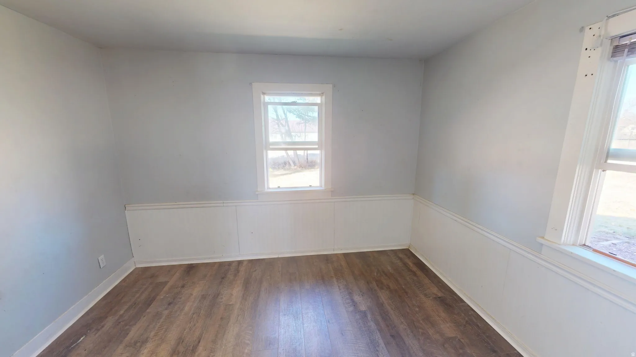 Spare room featuring dark wood-style floors and wainscoting