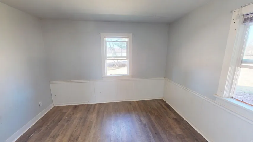 Spare room featuring dark wood-style floors and wainscoting