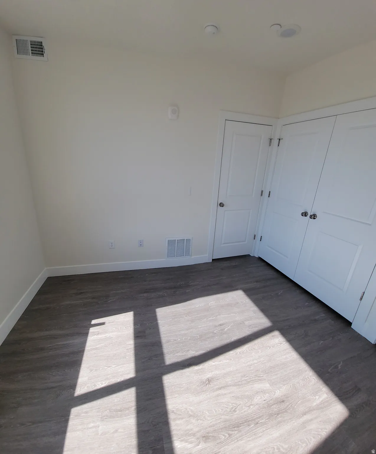 Unfurnished bedroom with dark wood-style flooring and a closet