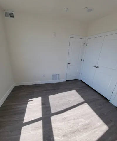 Unfurnished bedroom with dark wood-style flooring and a closet