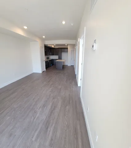 Unfurnished living room featuring dark wood-type flooring and recessed lighting