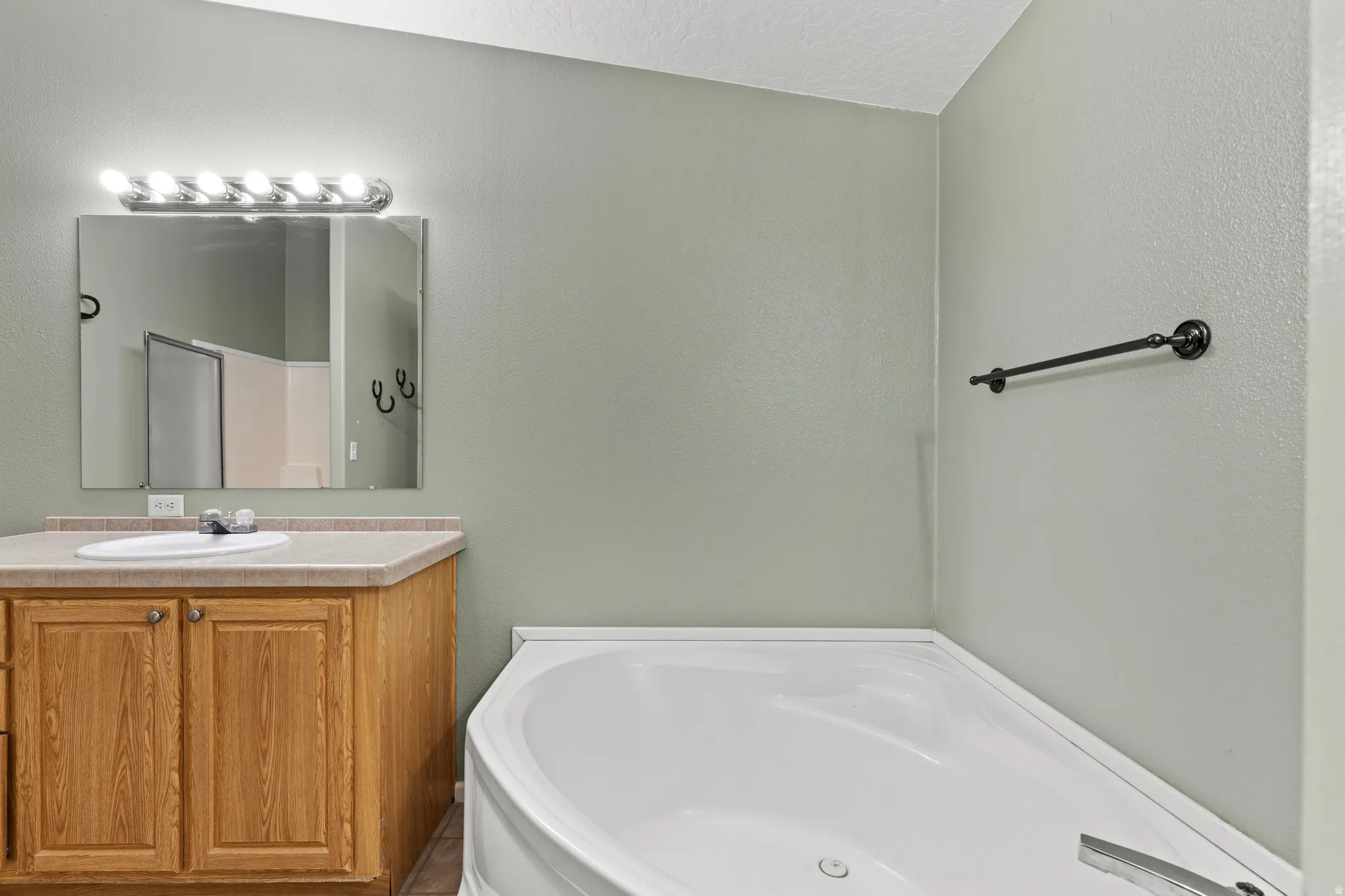 Full bath featuring vanity, a bath, a textured ceiling, and a textured wall