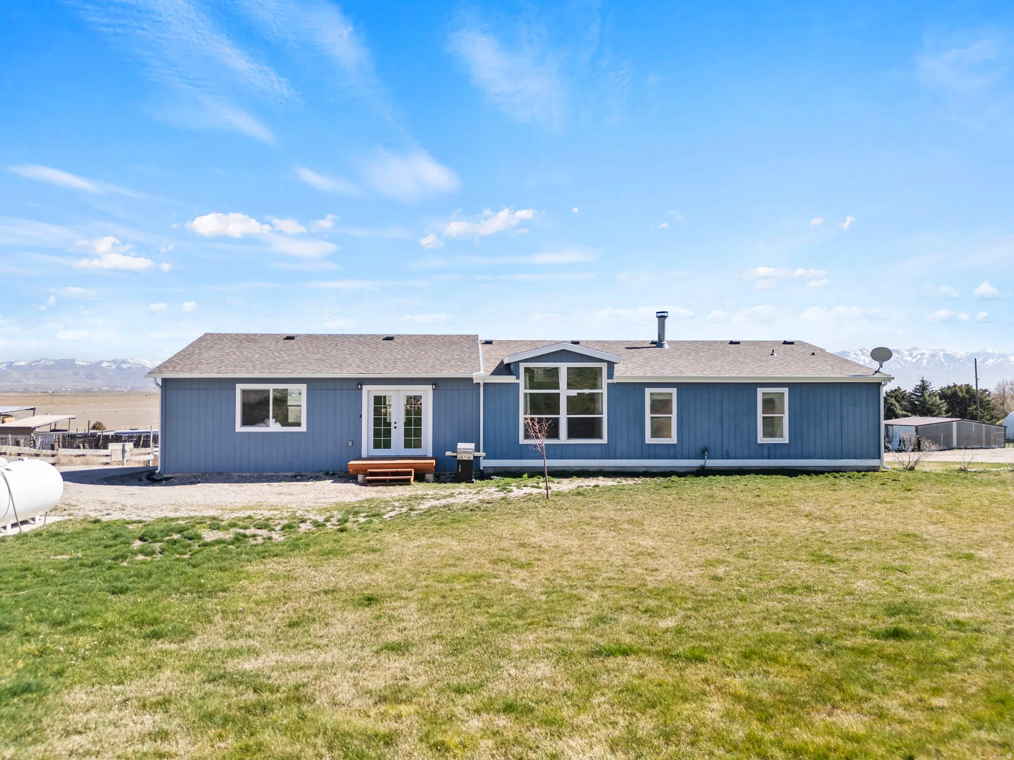 Back of property featuring a mountain view, a shingled roof, a yard, and french doors