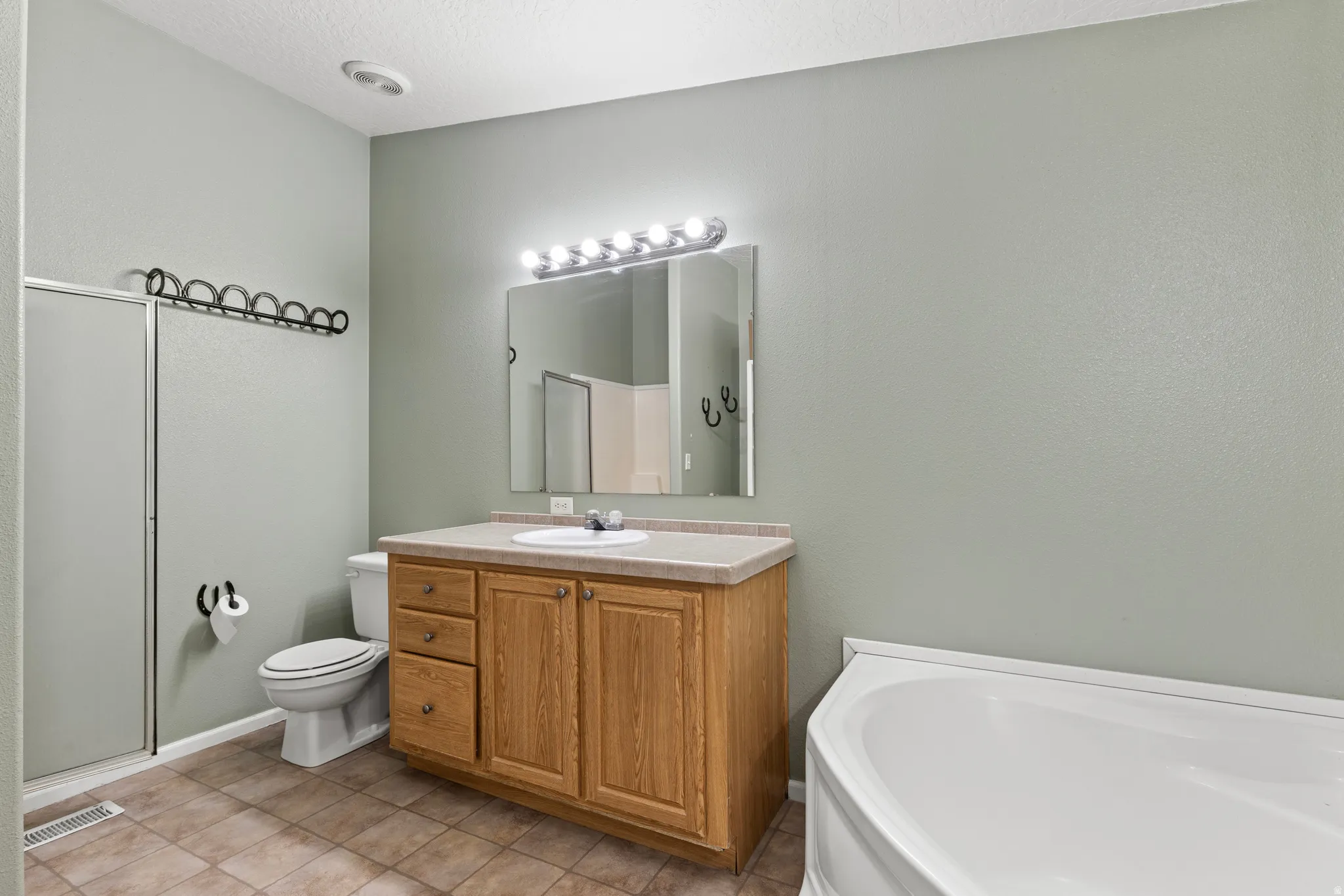 Bathroom featuring vanity, a bath, a shower stall, and light tile patterned floors