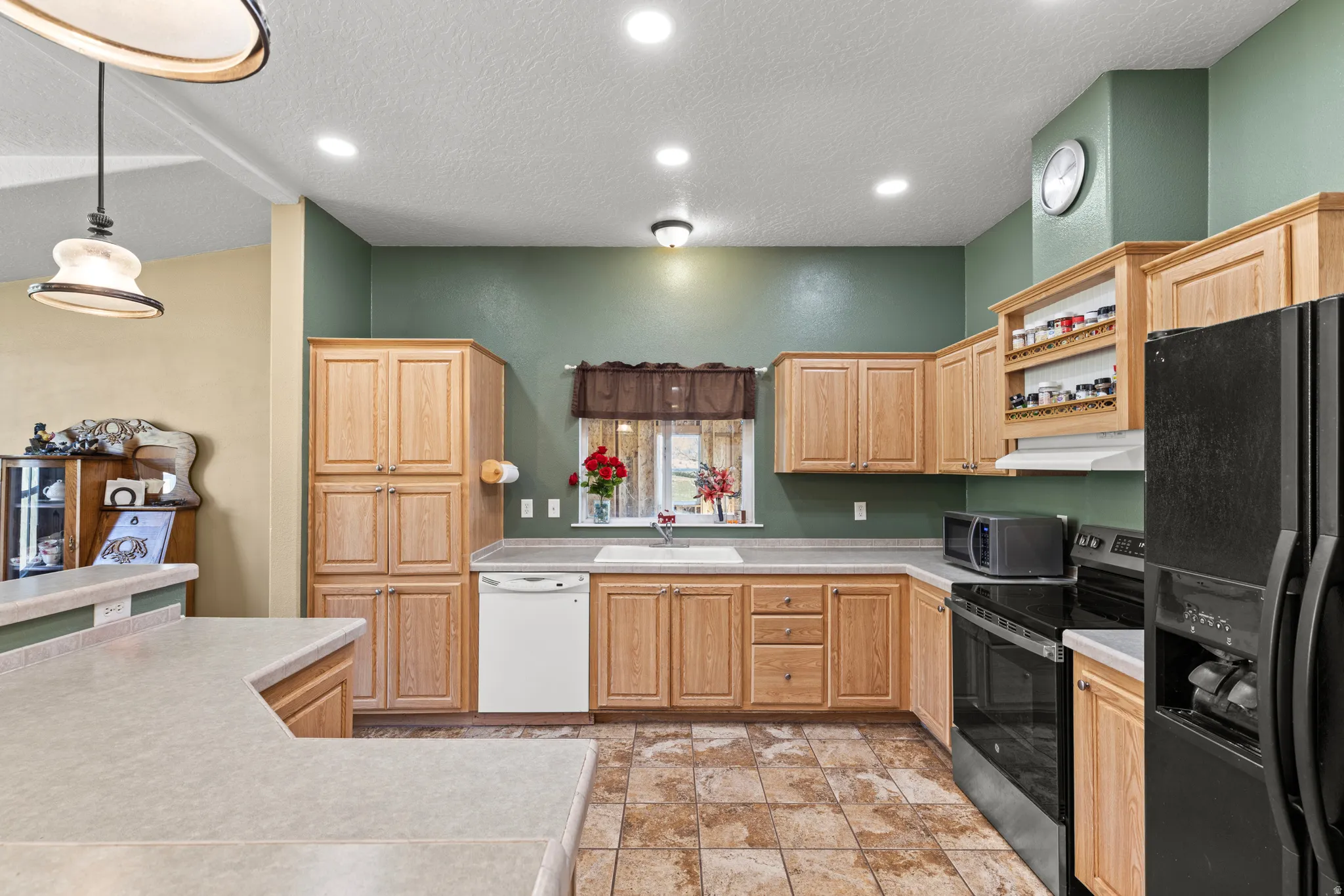 Kitchen featuring stainless steel appliances, a textured ceiling, light wood finish cabinetry, light countertops, and open shelves