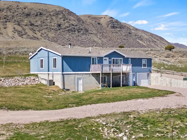 Rear view of house featuring a garage, driveway, a lawn, and a deck with mountain view
