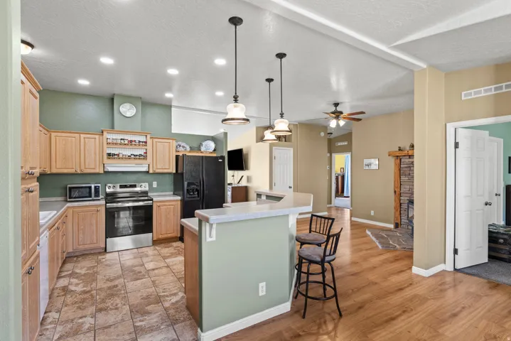 Kitchen featuring stainless steel appliances, light countertops, a breakfast bar, a kitchen island, and light wood finish cabinets