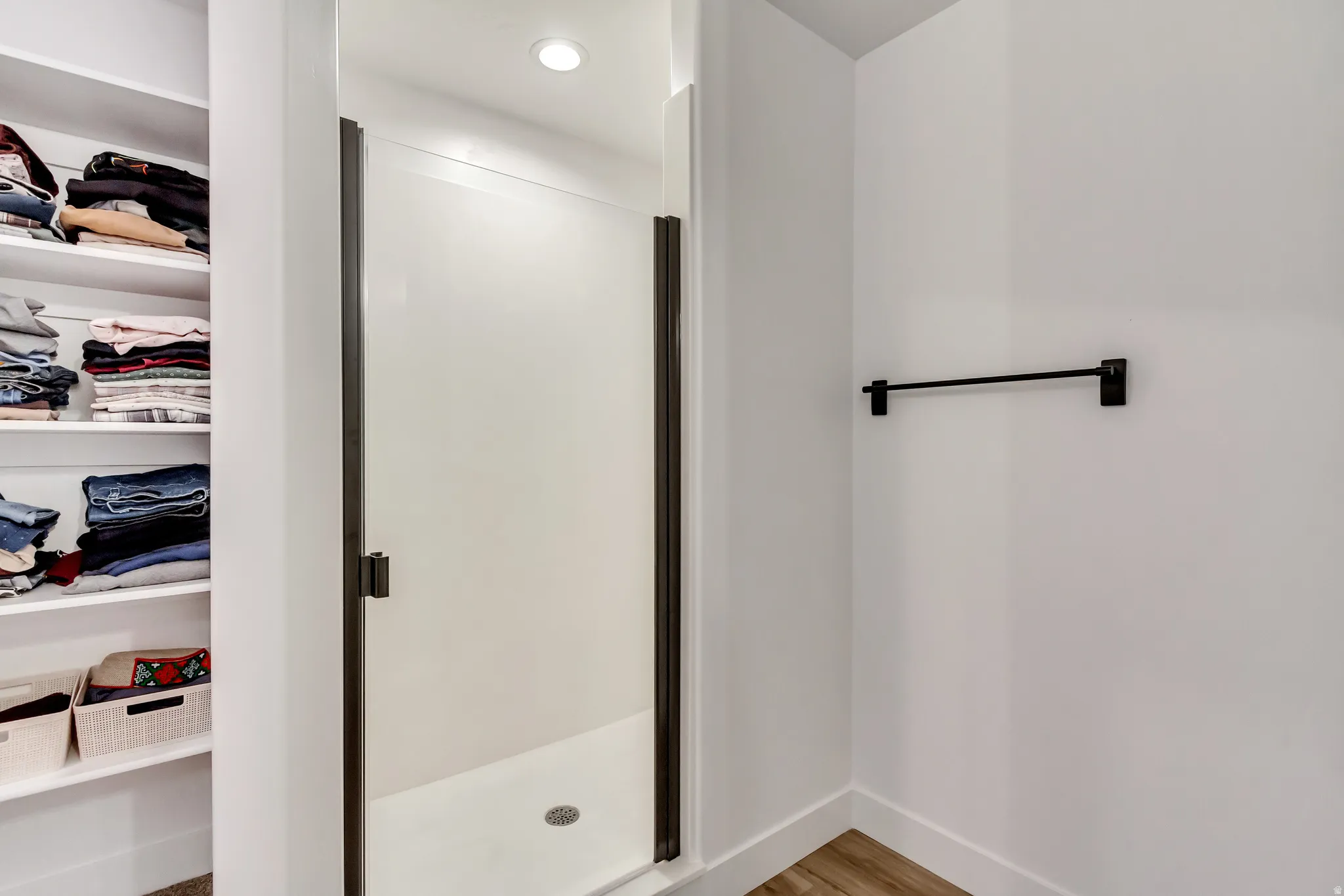Full bath featuring a shower stall, light wood finished floors, a spacious closet, and recessed lighting