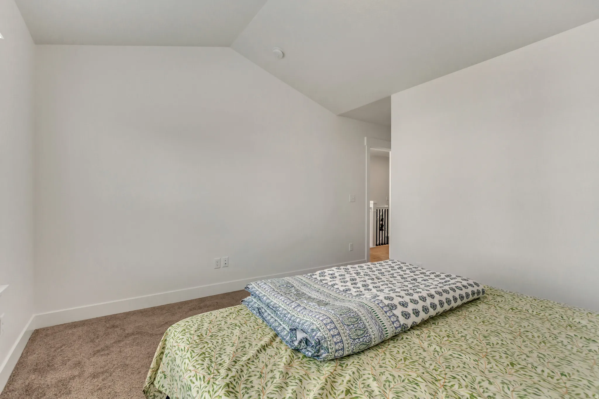 Bedroom featuring light carpet and vaulted ceiling