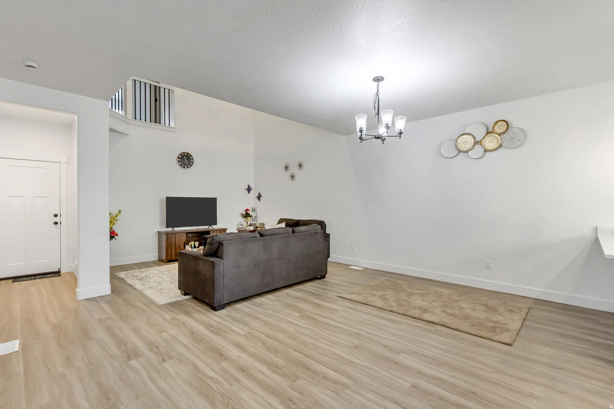 Living area with suspended lighting and light wood-style floors
