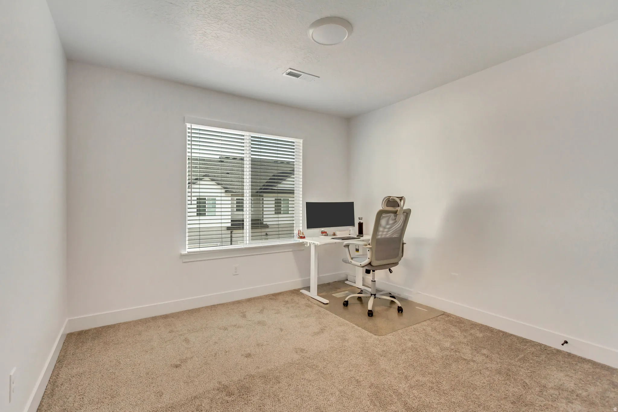 Office area featuring light carpet and baseboards