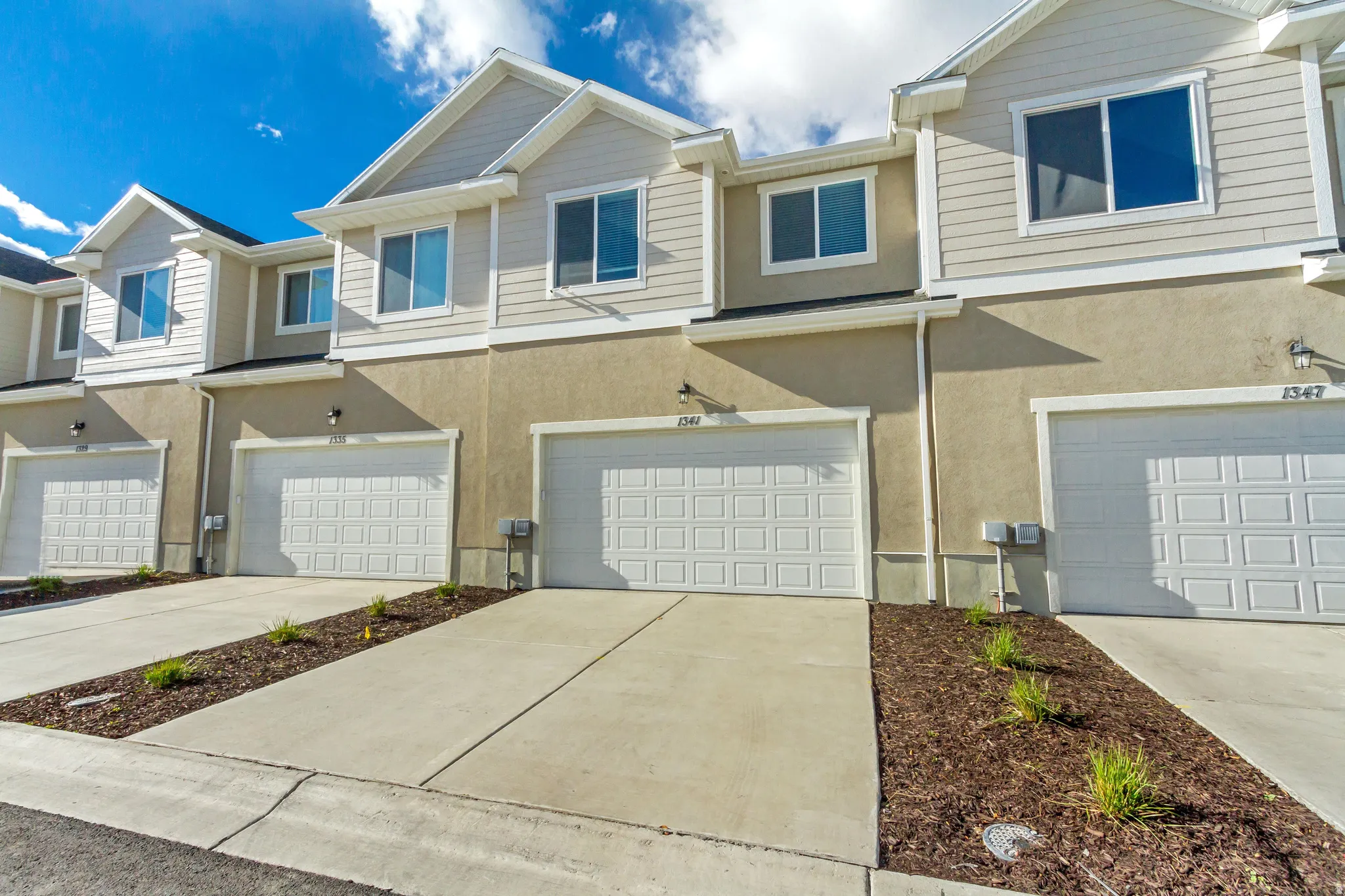 View of front facade featuring stucco siding, a garage, and driveway