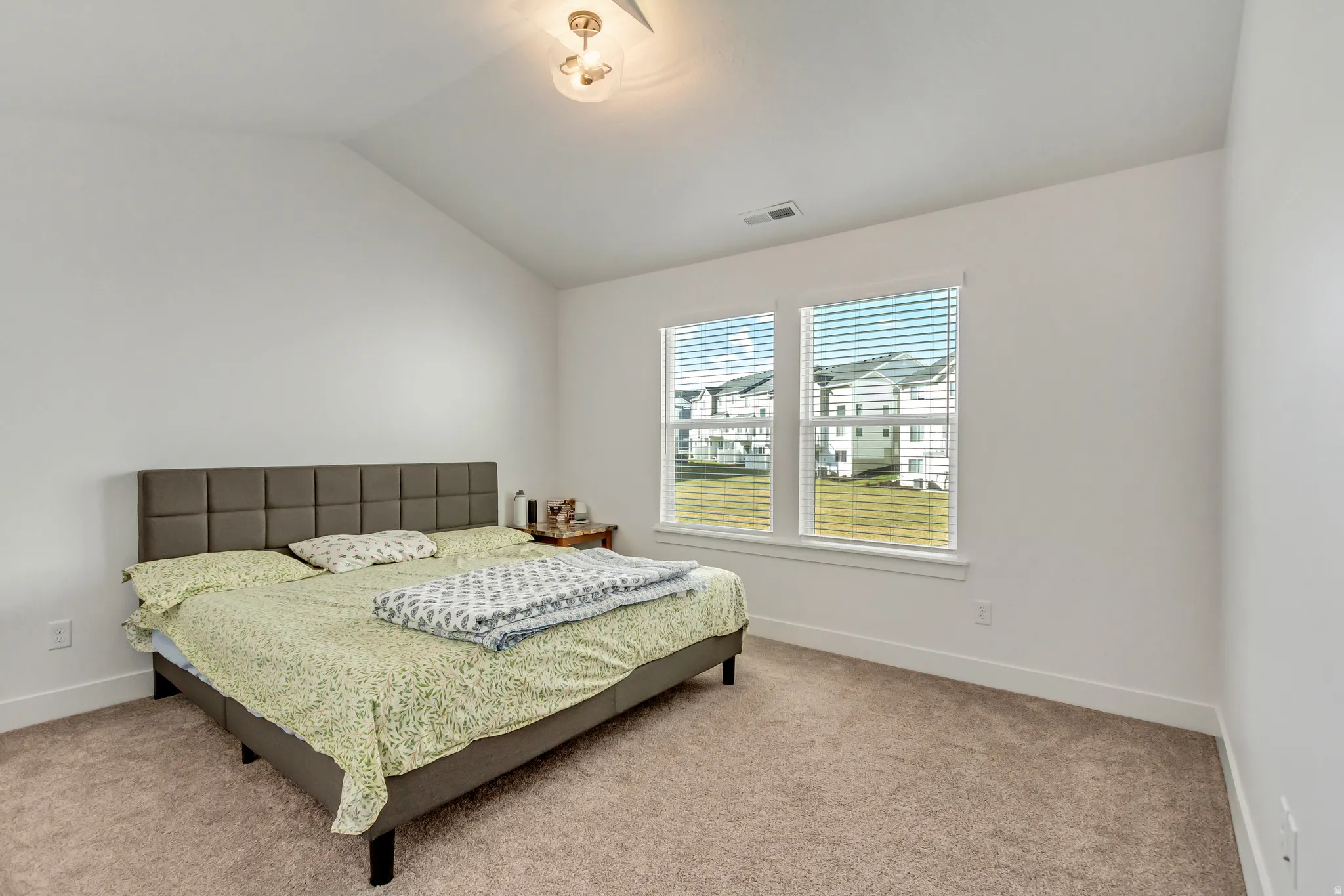 Bedroom featuring lofted ceiling and light carpet