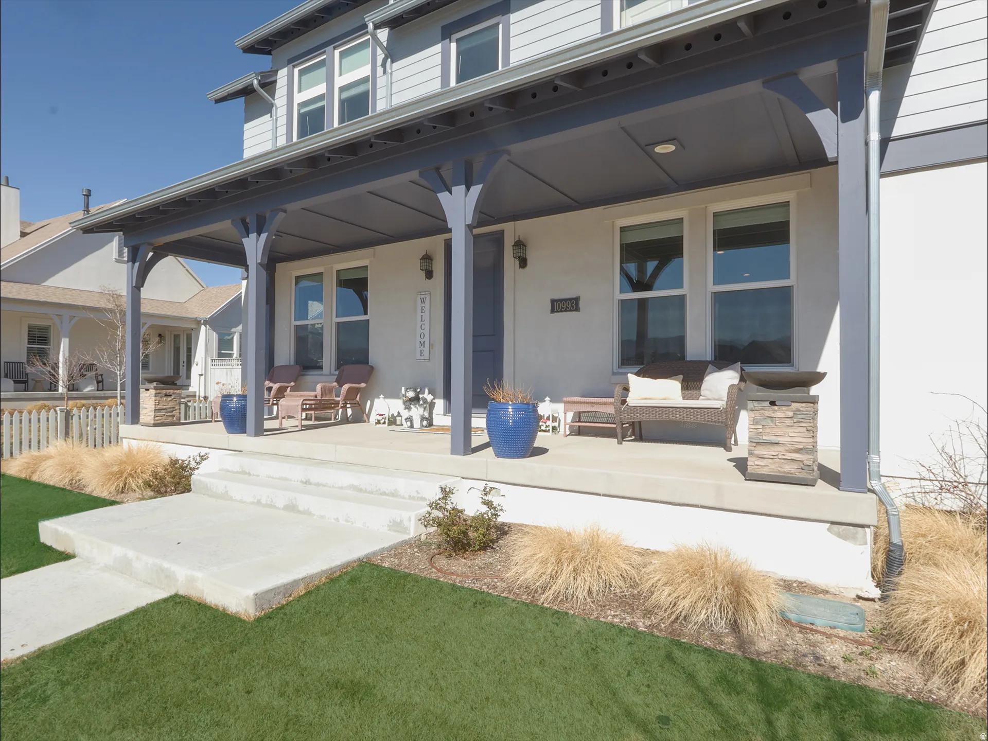 Covered front porch with white stucco facade and light blue siding