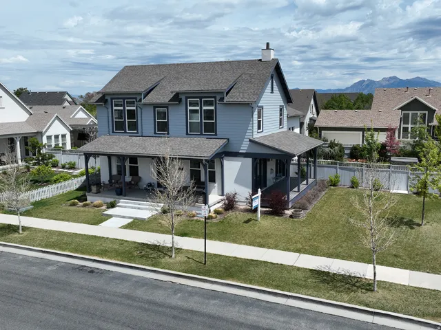 Two-story residence featuring light blue siding with white trim, a dark gray shingled roof, and a covered front porch