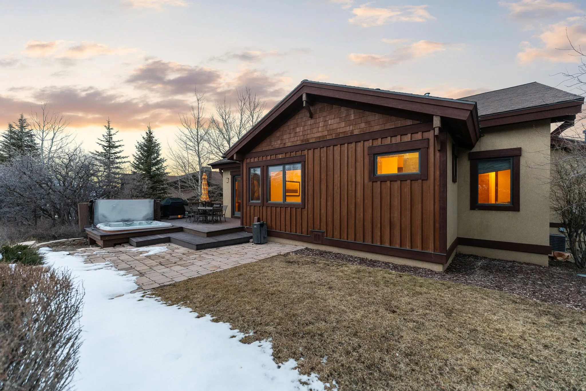 View of home's exterior with a hot tub, a lawn, board and batten siding, and a deck