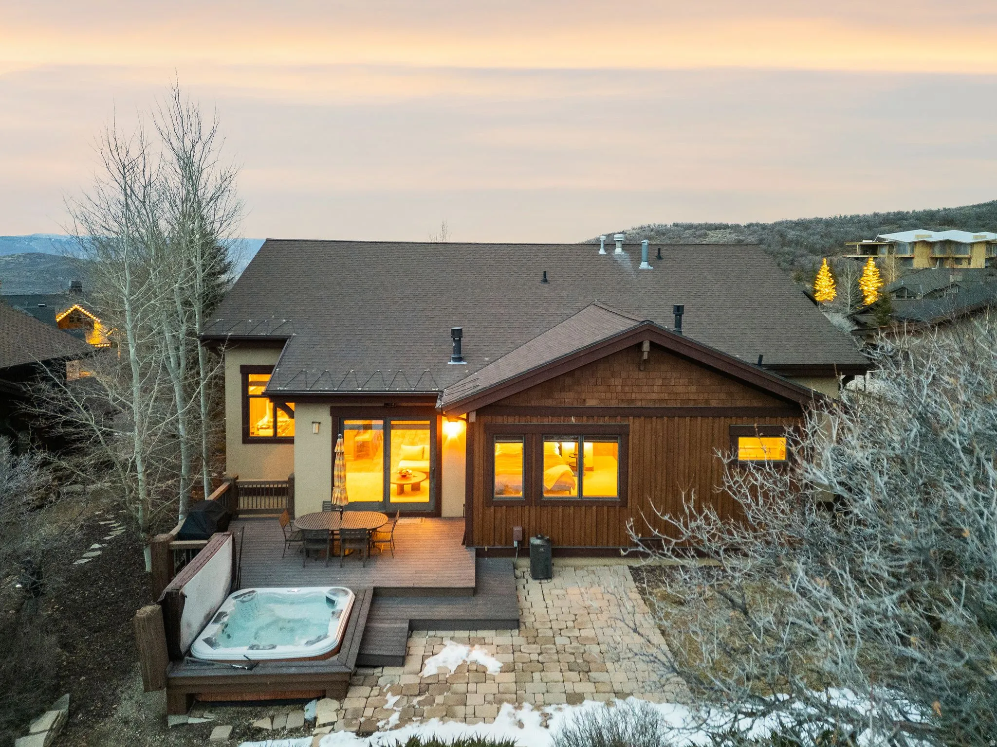 Rear view of property featuring a covered hot tub, outdoor dining area, a patio, and a shingled roof