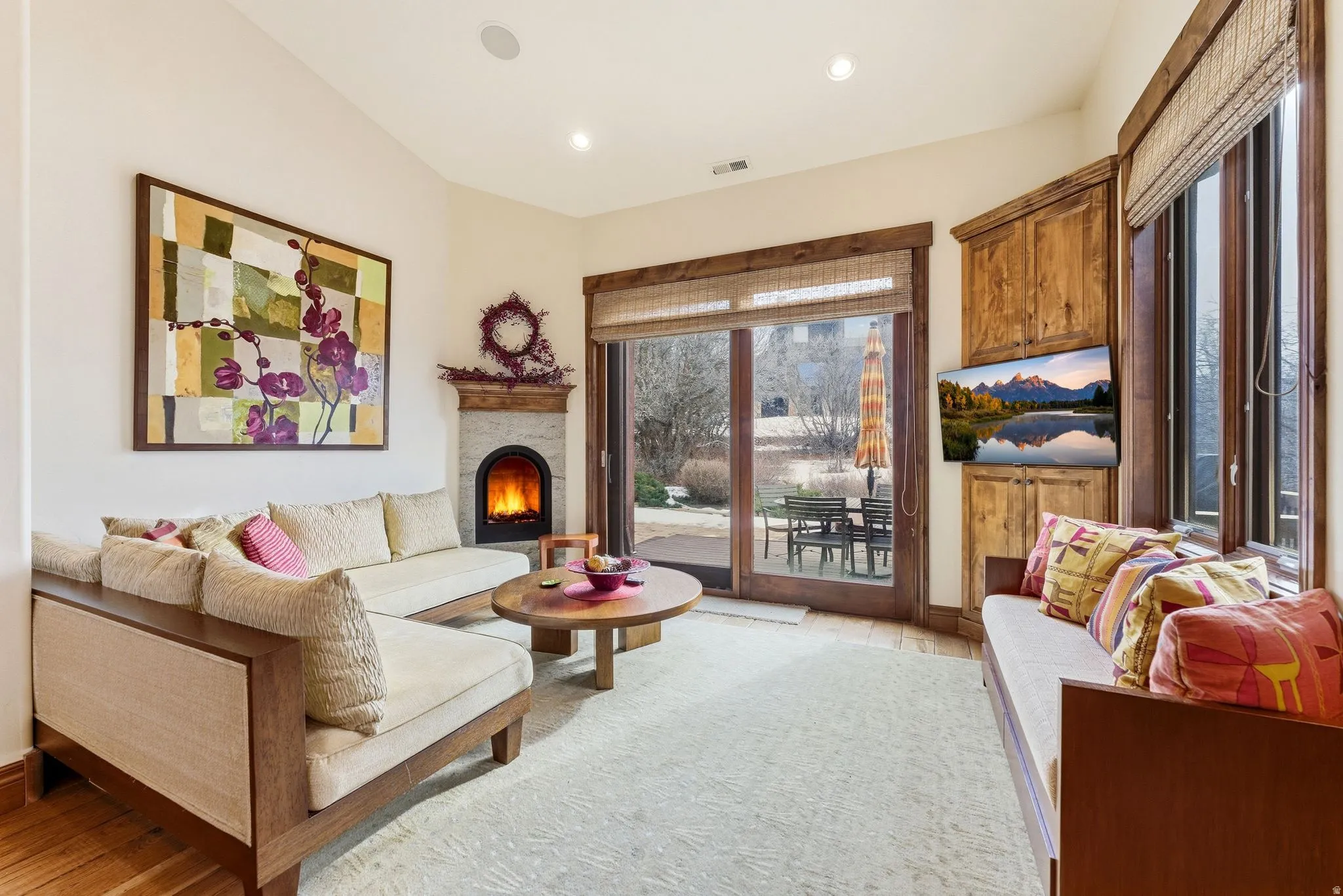 Living area with a lit fireplace, recessed lighting, and light wood finished floors