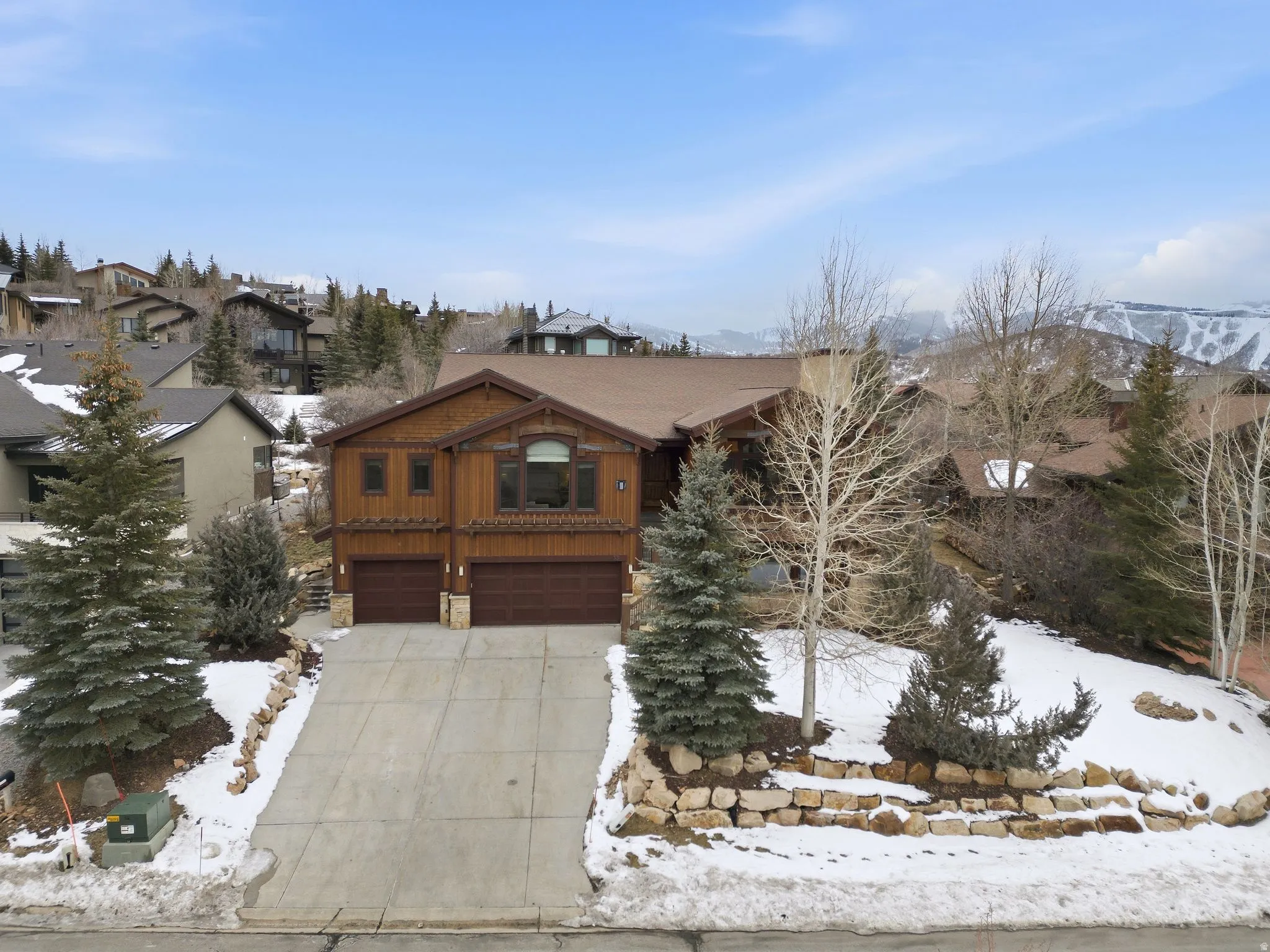 Chalet / cabin featuring a garage, driveway, and stone siding