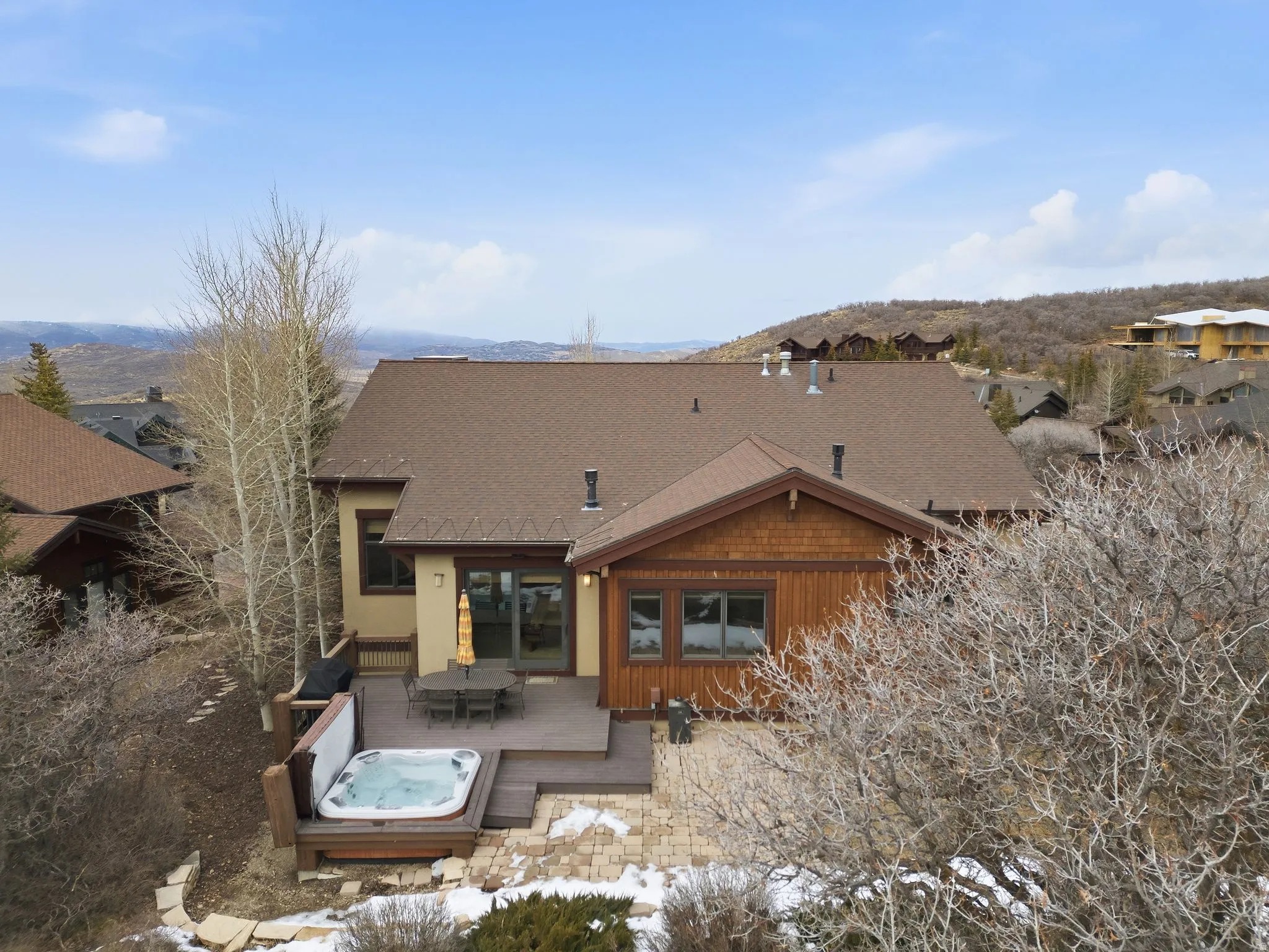 Rear view of property with a hot tub, outdoor dining space, and roof with shingles