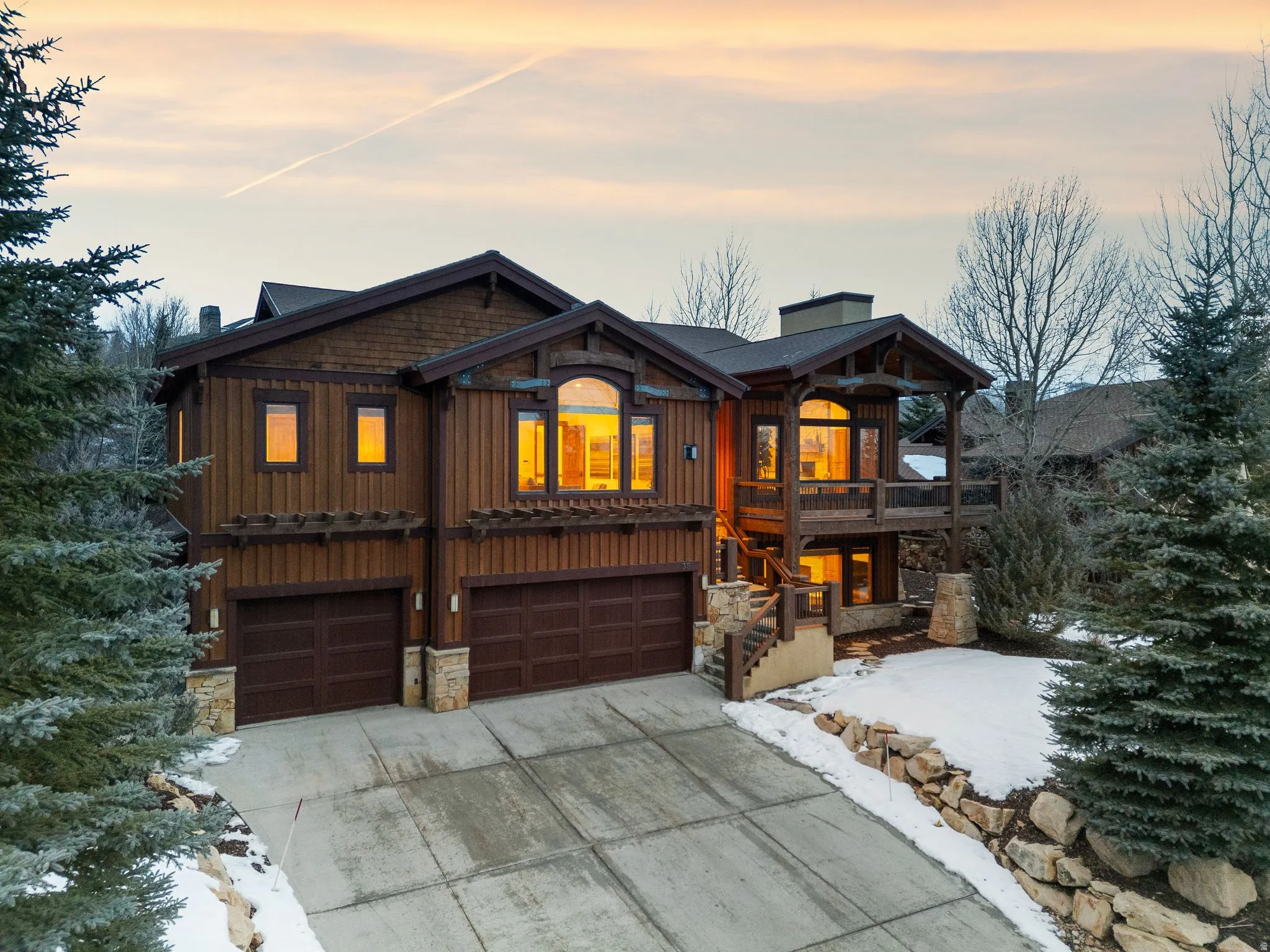 Rustic home featuring a garage, concrete driveway, board and batten siding, and stone siding