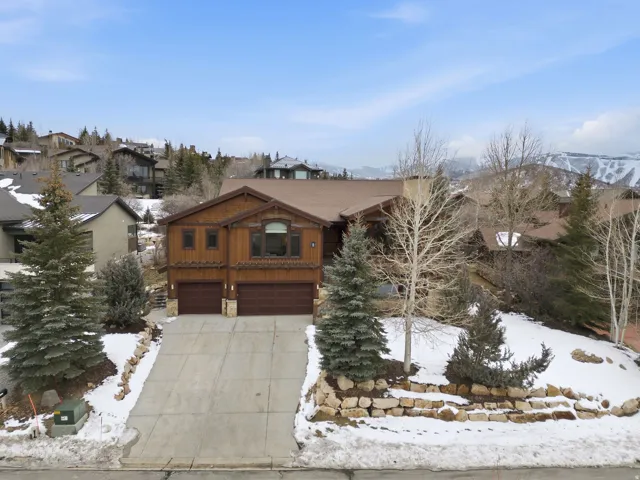 Chalet / cabin featuring a garage, driveway, and stone siding