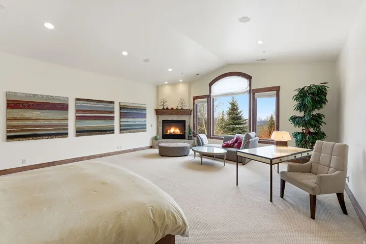 Bedroom featuring light colored carpet, a lit fireplace, and recessed lighting