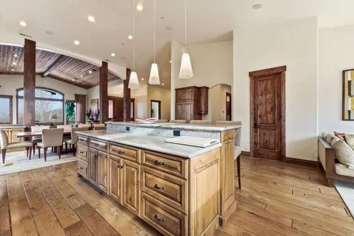 Kitchen with open floor plan, a kitchen breakfast bar, light wood-style flooring, hanging light fixtures, and a spacious island