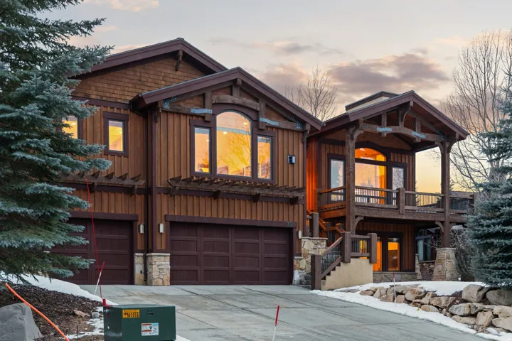 Chalet / cabin with board and batten siding, a garage, stone siding, and concrete driveway