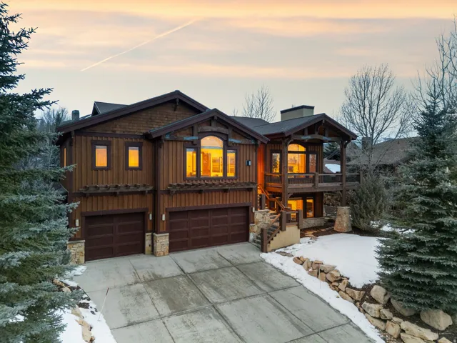 Rustic home featuring a garage, concrete driveway, board and batten siding, and stone siding