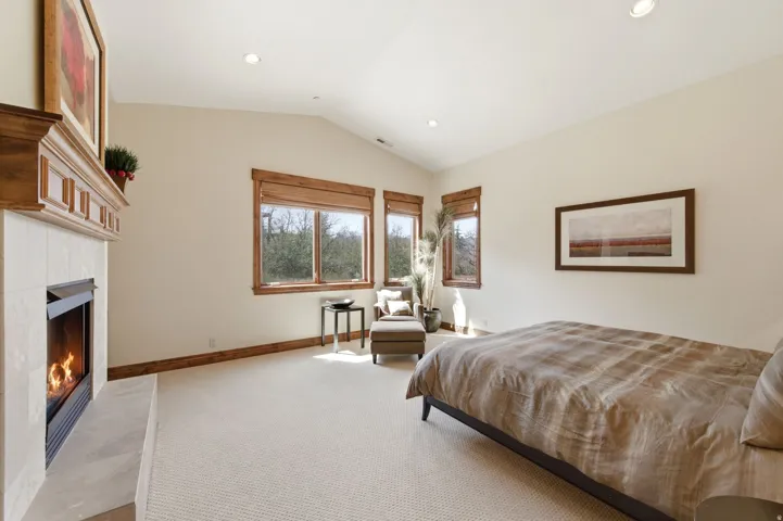 Bedroom featuring a tiled fireplace, light colored carpet, and recessed lighting