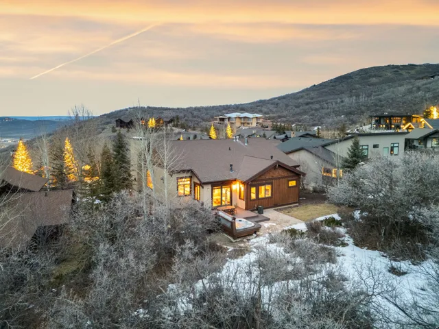 Snow covered back of property with a mountain view and a patio