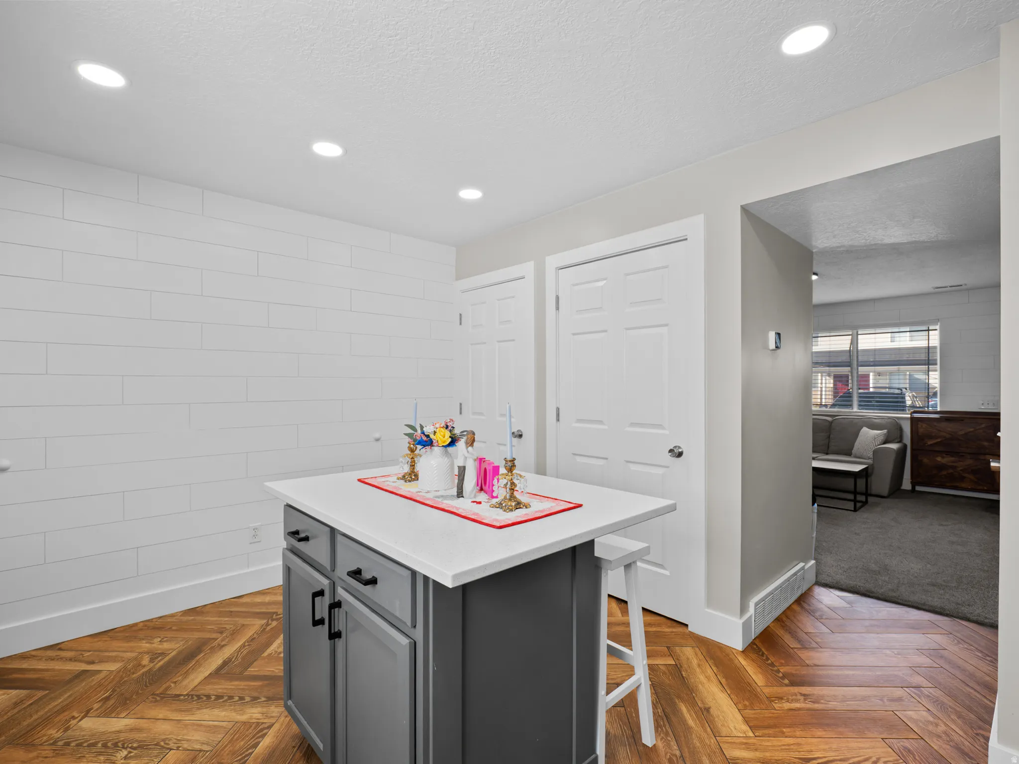 Kitchen with a breakfast bar area, a kitchen island, parquet flooring, a textured ceiling, and gray cabinets