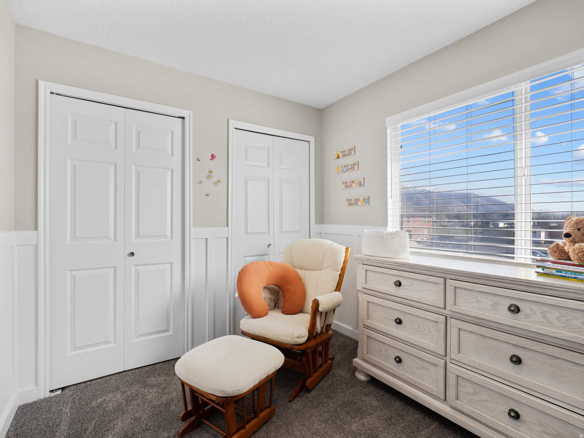Sitting room with a wainscoted wall, dark colored carpet, and a decorative wall