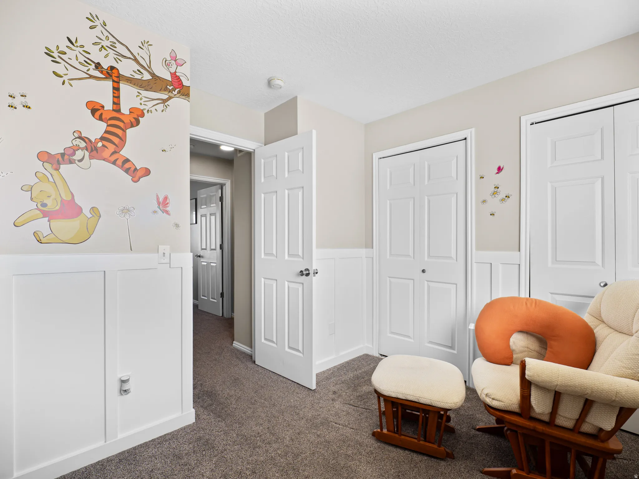 Sitting room featuring a wainscoted wall, a decorative wall, and dark carpet