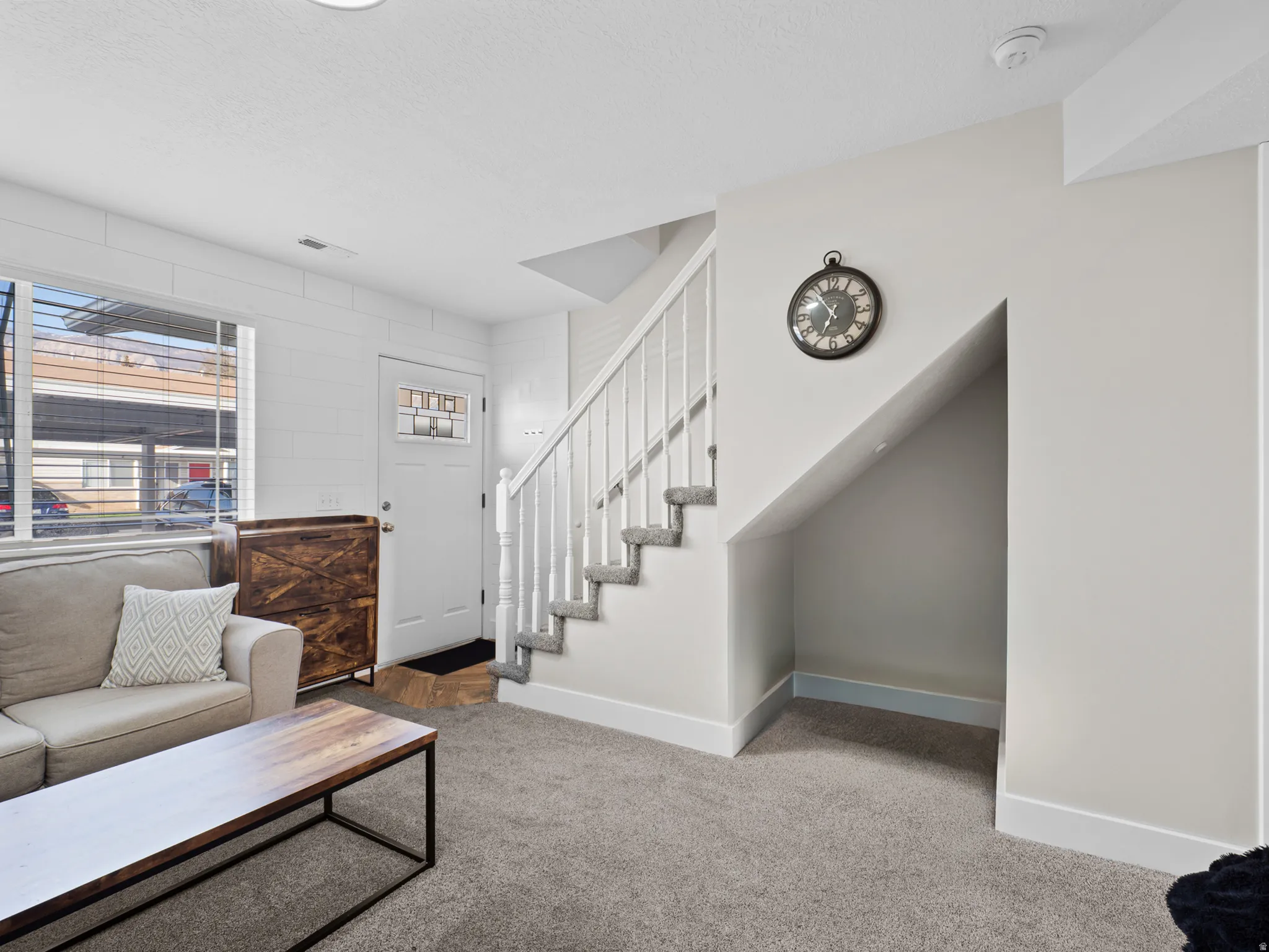 Carpeted living area with baseboards and stairway