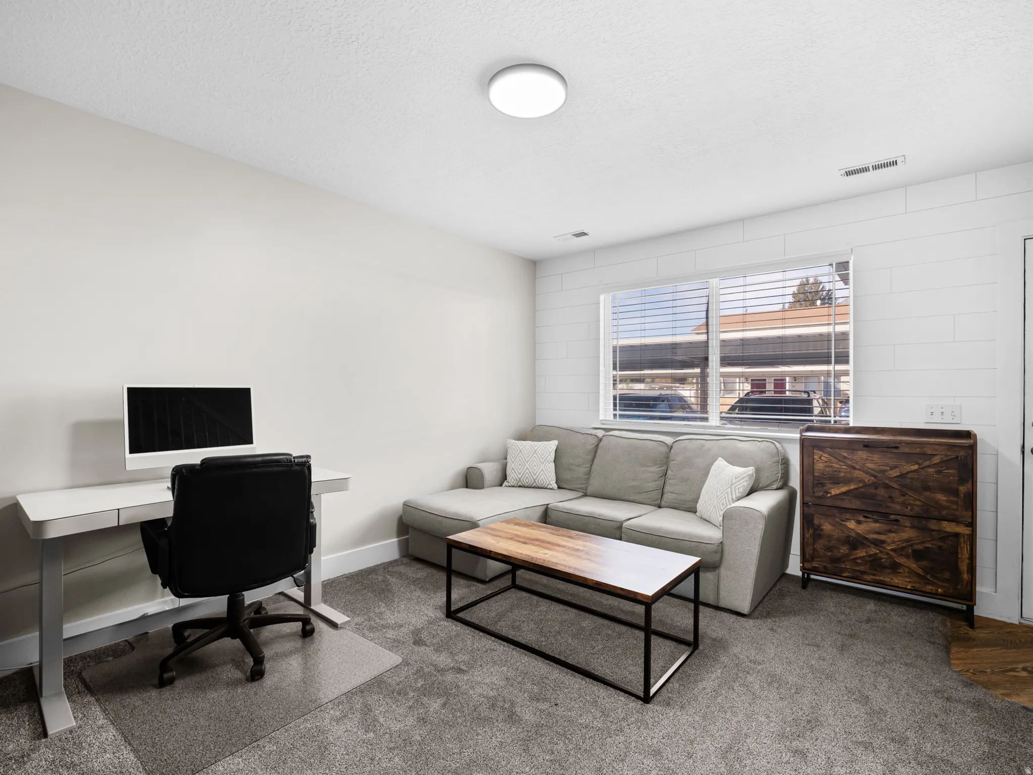 Office with carpet floors and a textured ceiling