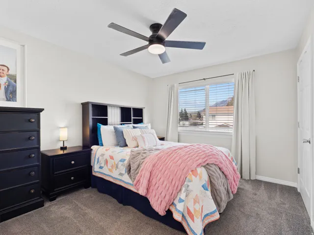 Carpeted bedroom with a ceiling fan