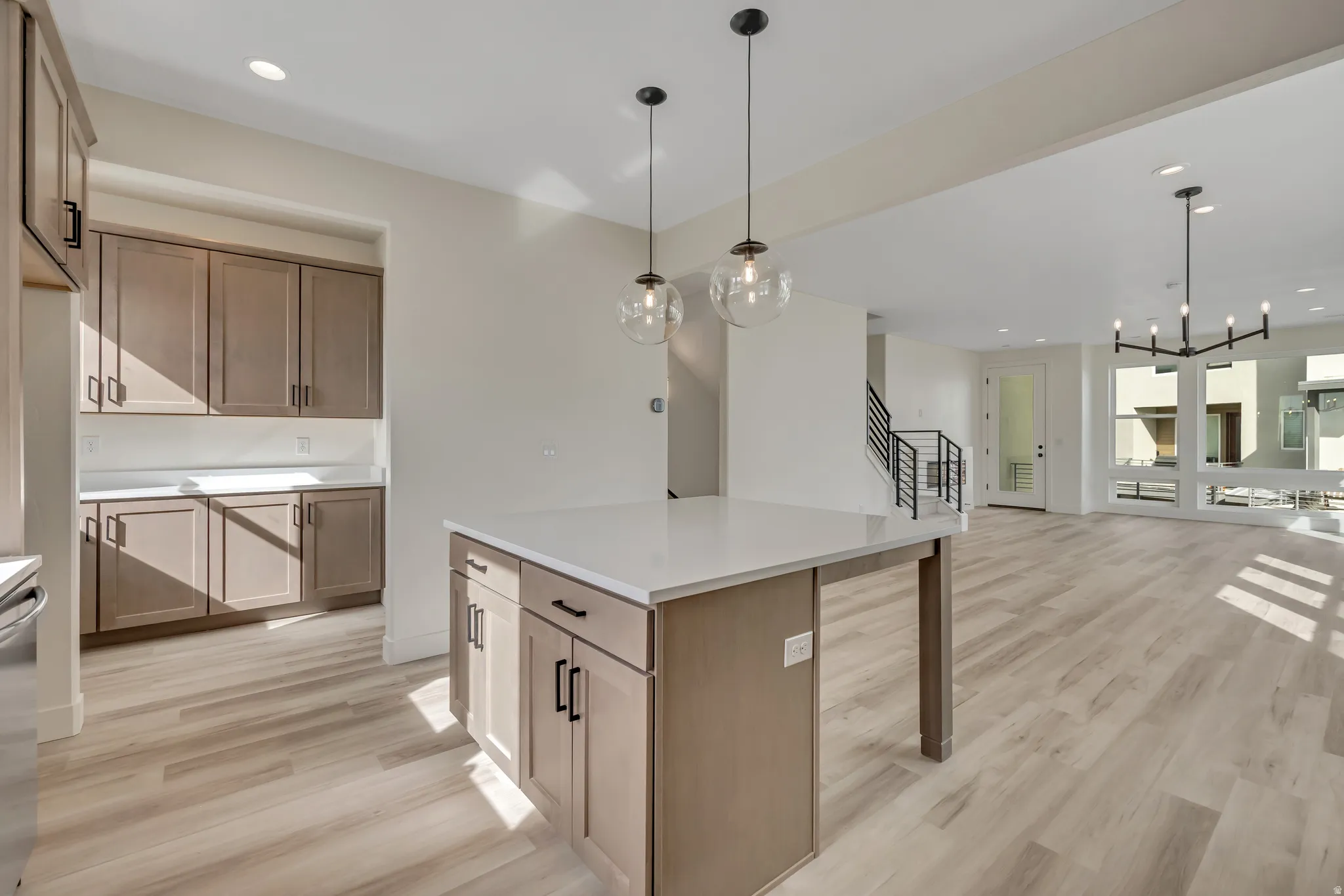 Kitchen featuring light wood-style flooring, open floor plan, light countertops, a kitchen island, and stainless steel dishwasher