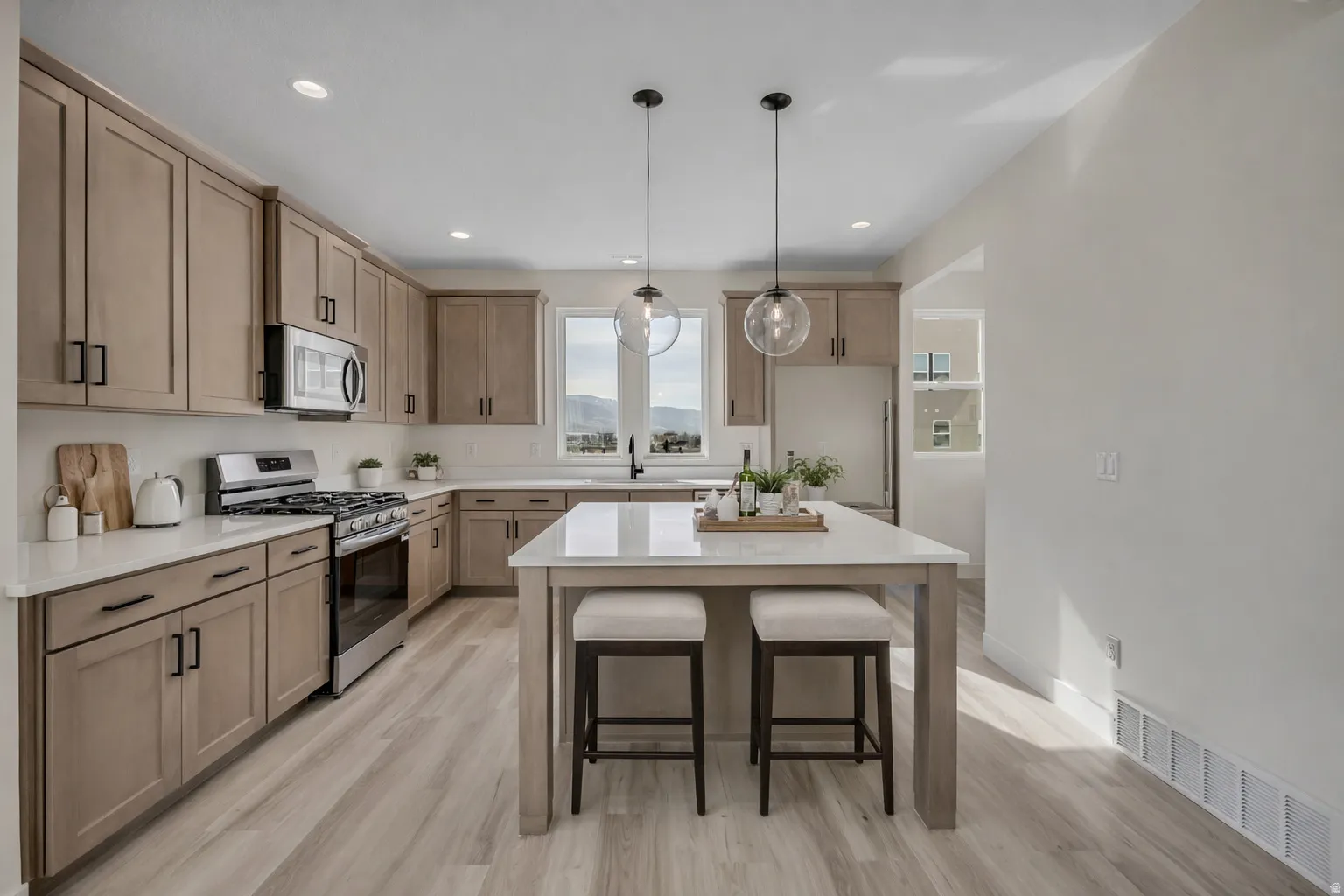 Kitchen with stainless steel appliances, a breakfast bar, light wood-style flooring, decorative light fixtures, and a center island