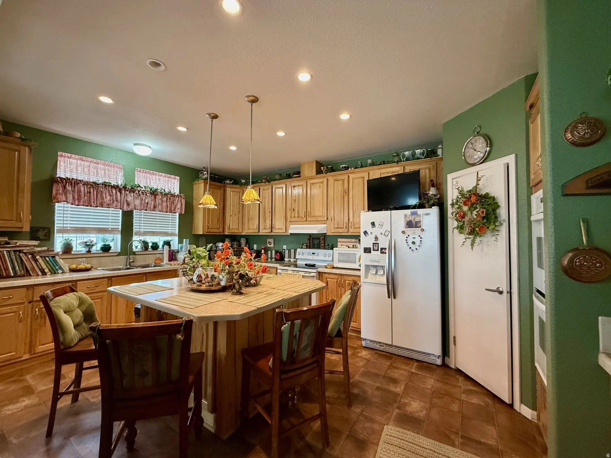 Kitchen with white appliances, a breakfast bar area, a kitchen island, tile countertops, and light wood finish cabinetry